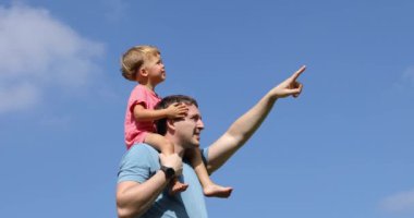 Çocuğun omuzlarına uzağa işaret eden adamla