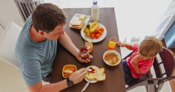 Ojciec z dzieckiem jedzą śniadanie razem z nimi — Wideo stockowe