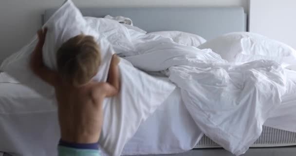 Застелить постель, ребенок заправляет кровать в комнате после пробуждения — стоковое видео