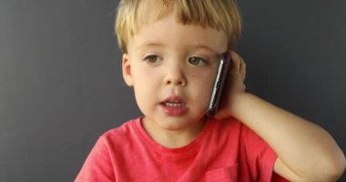 Çocuk cep telefonuyla konuşuyor. Hareket eden telefon ile oynayan bebek. bir çocuğun elinde yeni dijital teknolojiler. Smartphone ile çocuk portresi