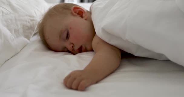 Imádnivaló baba alszik a fehér ágyban — Stock videók