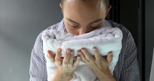 Женщина нюхает чистое полотенце — стоковое видео