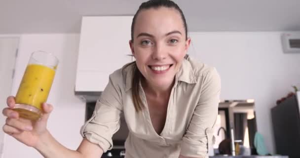 Mulher sorridente com bebida saudável na cozinha — Vídeo de Stock