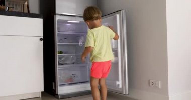 Küçük çocuk süt almak için buzdolabı açar