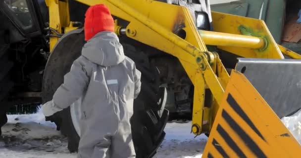 Small child approaches tractor touches wheel — Stock Video