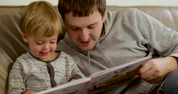 Père avec petit fils lire livre maison — Video