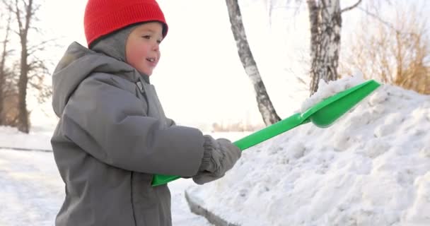 Niño muestra pala verde nieve — Vídeo de stock