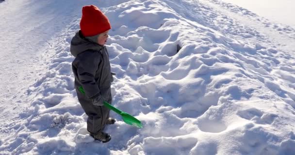 Kind mit Spachtel steht mitten in Schneewehe — Stockvideo