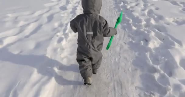 Маленький ребенок бежит по дороге зимой — стоковое видео