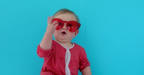 Lindo bebé con niño en gafas de sol rojas — Vídeo de stock