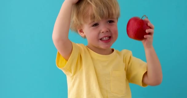 Kid med röd läcker äpple på blå bakgrunds — Stockvideo