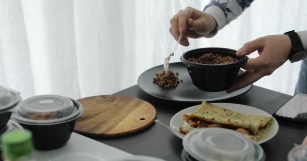 Человек кладет гречневую кашу на тарелку — стоковое видео