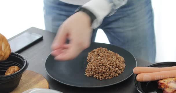 Hombre toma pedazo de carne cocida y pone gachas de trigo sarraceno — Vídeo de stock