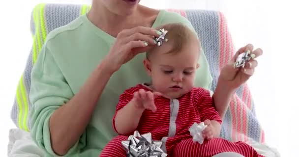 Мати прикрашає дитячу голову пакувальними бантами — стокове відео