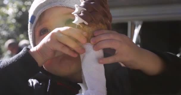 Милый маленький мальчик лижет мороженое в конусе — стоковое видео