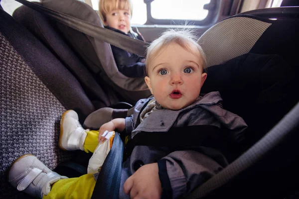 Linda chica y niño sentado en el asiento trasero del coche — Foto de Stock