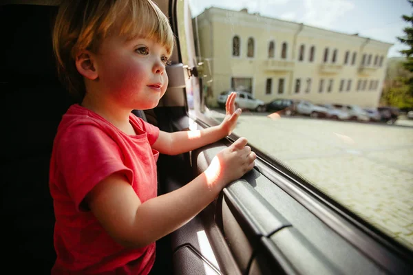 Niño mirando a través de la ventana del coche — Foto de Stock