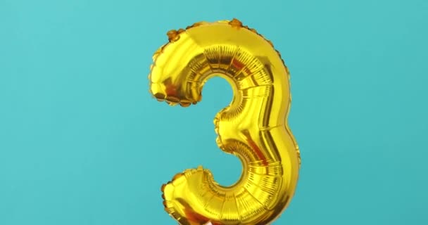 Gold foil number 3 celebration balloon on a blue — Stock Video