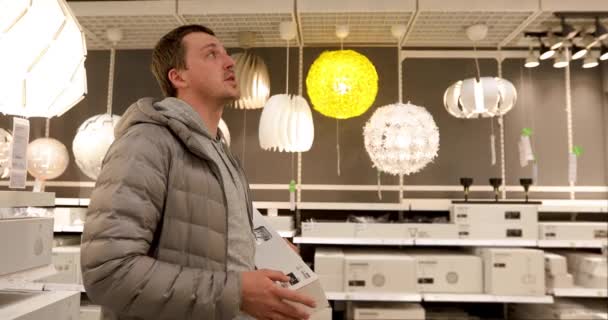 Alleenstaande man houdt een gloeilamp in de huishoudelijke winkel — Stockvideo