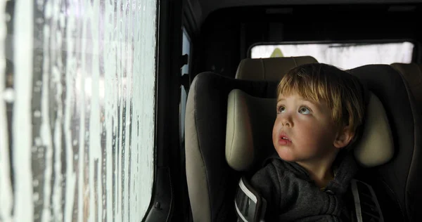 Niño en un asiento de coche en el lavado de coches — Foto de Stock
