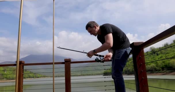 Рыбак бросает в озеро рыболовный снаряд — стоковое видео