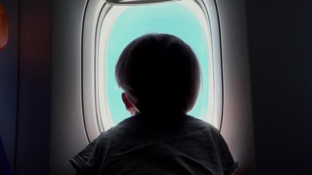 Boy on the seat looking out an airplane window — Stock Video