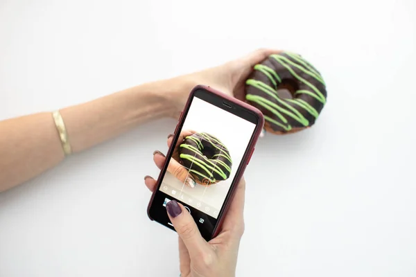Mulher fotografando donut com smartphone — Fotografia de Stock
