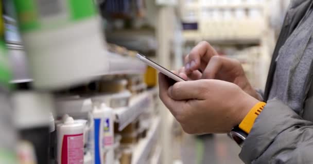 Hombre stand uso teléfono hold jamón en ferretería — Vídeos de Stock