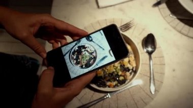 Akşam yemeğinde telefonda yemek fotoğrafını çeken kişi