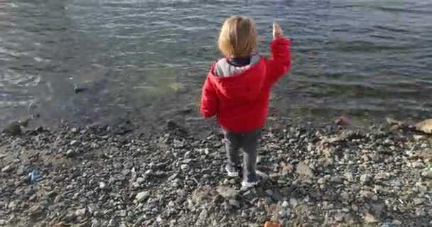 Chico lanza una piedra al agua — Vídeos de Stock