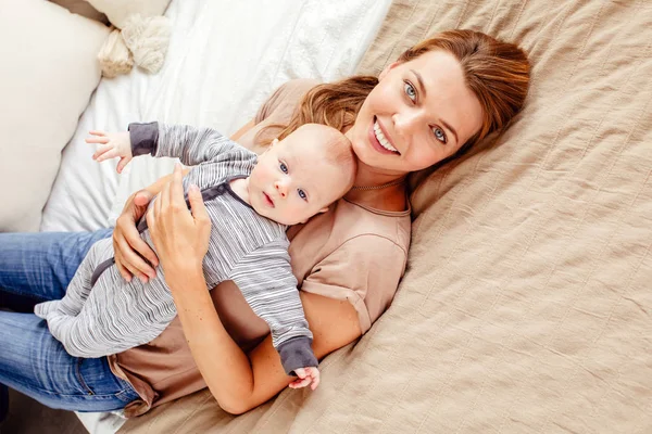 Sorridente madre con bambino sdraiato sul letto — Foto Stock