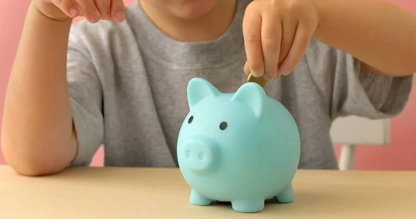 Kleiner Junge steckt Münzen in ein Sparschwein — Stockfoto