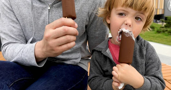 Dad and son eating ice cream on bench — Stock Photo, Image