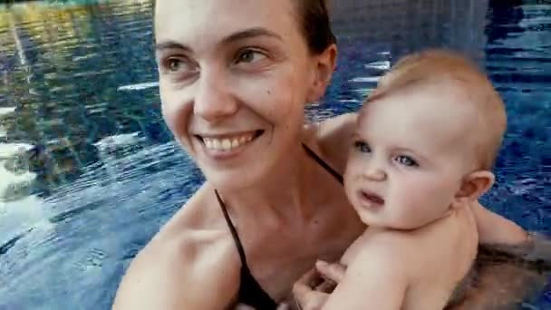 Joven madre feliz con el bebé en la piscina — Vídeos de Stock