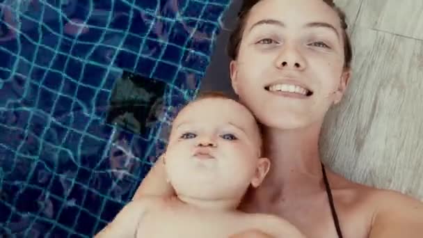 Joven madre feliz con el bebé en la piscina — Vídeos de Stock