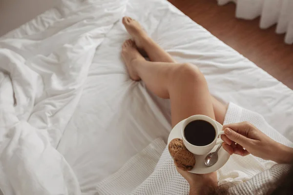 Vacker flicka dricker kaffe med kakor säng — Stockfoto