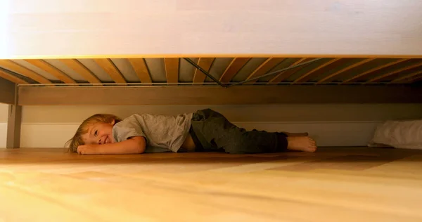 Barn som letar efter något under sängen — Stockfoto