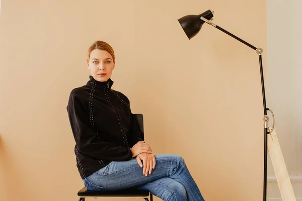 Short-haired woman in chair in front of studio light — Stock Photo, Image