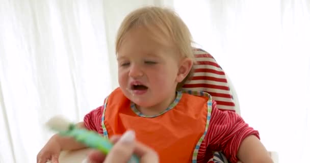 Ребенок в детском кресле плачет во время еды — стоковое видео