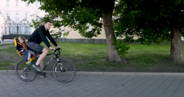 Mann fährt Fahrrad mit Kind im Sicherheitssitz — Stockvideo