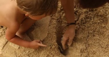 Kumlu plajda yüzsüz ebeveyn ile oynayan çocuk