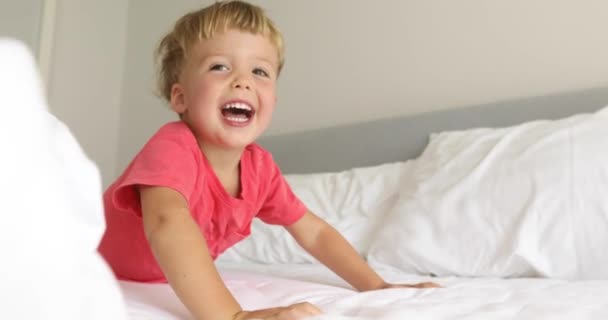 Criança engraçada rindo e brincando na cama — Vídeo de Stock