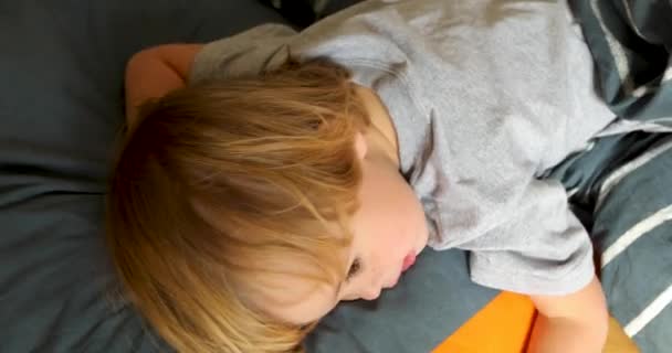 Niño cansado acostado en la cama y mirando a lo largo — Vídeos de Stock