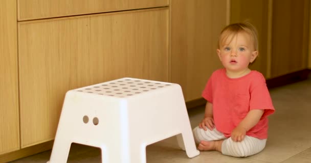 Bedårande Kid sitter på golvet med vit stol — Stockvideo