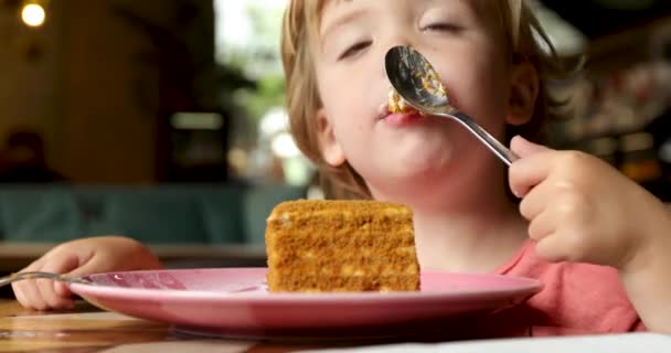 Малыш сладкоежка облизывает ложку с тортом — стоковое видео
