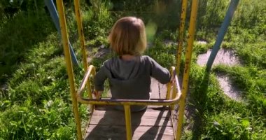 Çocuk eski salıncak bahçesinde oturan