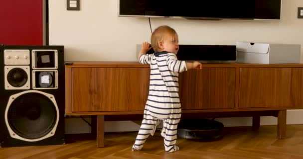 Baby in overalls staand in woonkamer — Stockvideo
