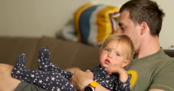 Отец отдыхает с ребенком на диване — стоковое видео