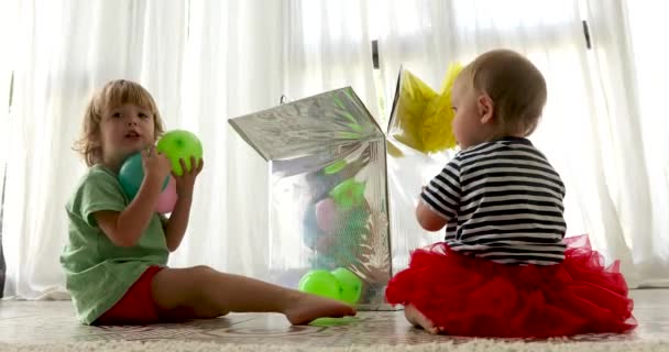 Anak-anak lucu duduk di lantai dan bermain dengan balon berwarna-warni — Stok Video