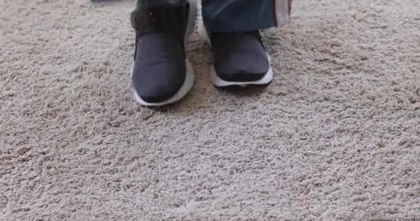Человек снимает кроссовки на мягком ковре — стоковое видео